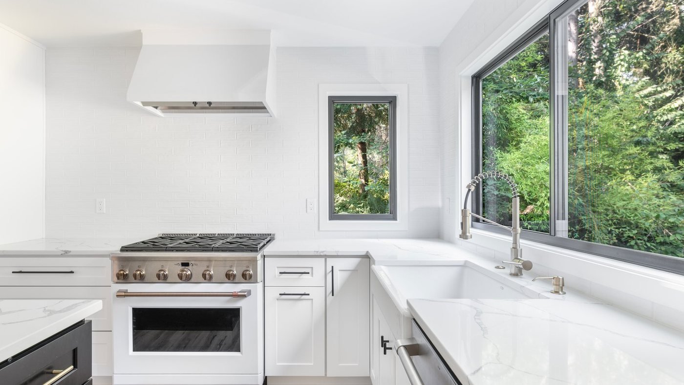 Kitchen with a professional range, marble style counters, and a large window
