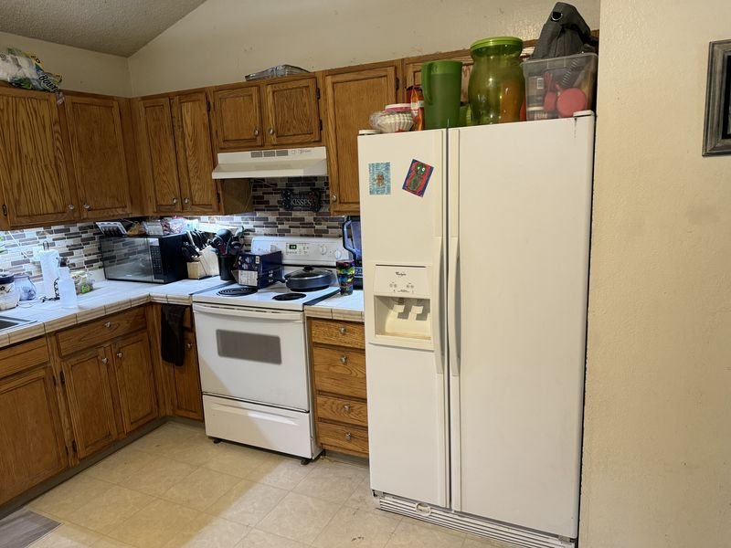 Kitchen before: oak cabinets, white appliances and light sheet flooring