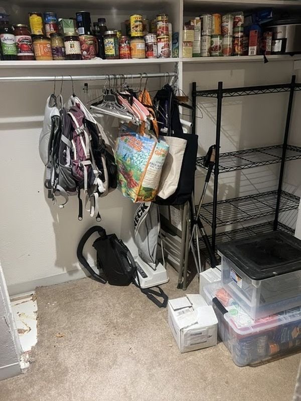 Walk-in closet before: wire shelving with bags and boxes stacked on the carpet