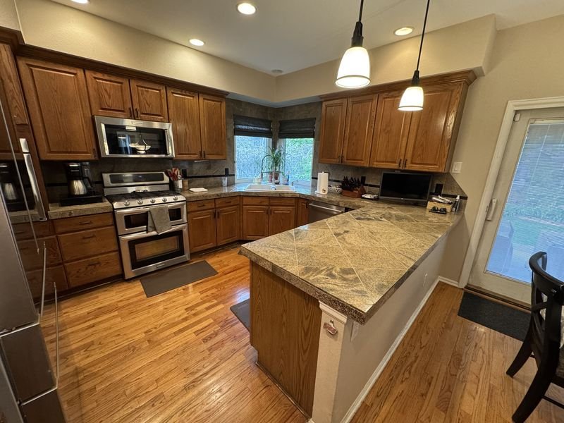 Kitchen before: honey oak cabinets, granite counters and a peninsula