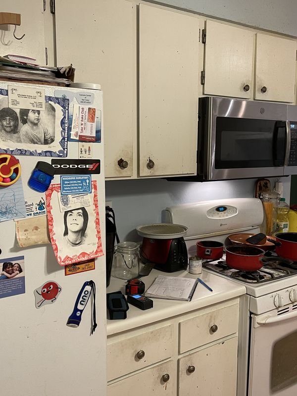 Kitchen before: worn cream cabinet doors, white appliances and cluttered counters