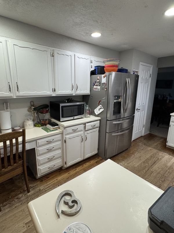 Kitchen before: dated white cabinets, worn laminate counters and a cluttered peninsula