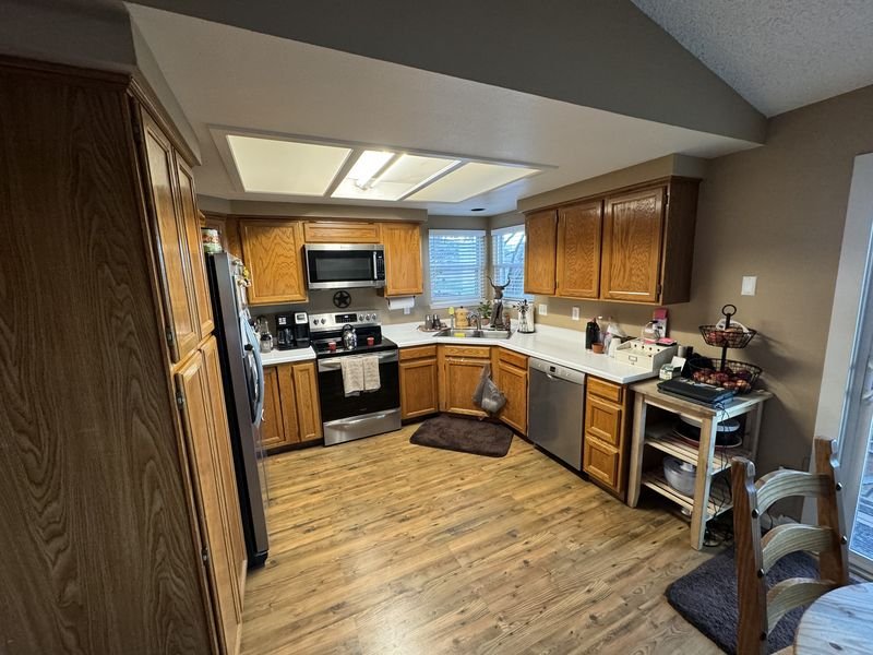 Kitchen before: honey oak cabinets and a boxed fluorescent ceiling panel, with one window over the sink