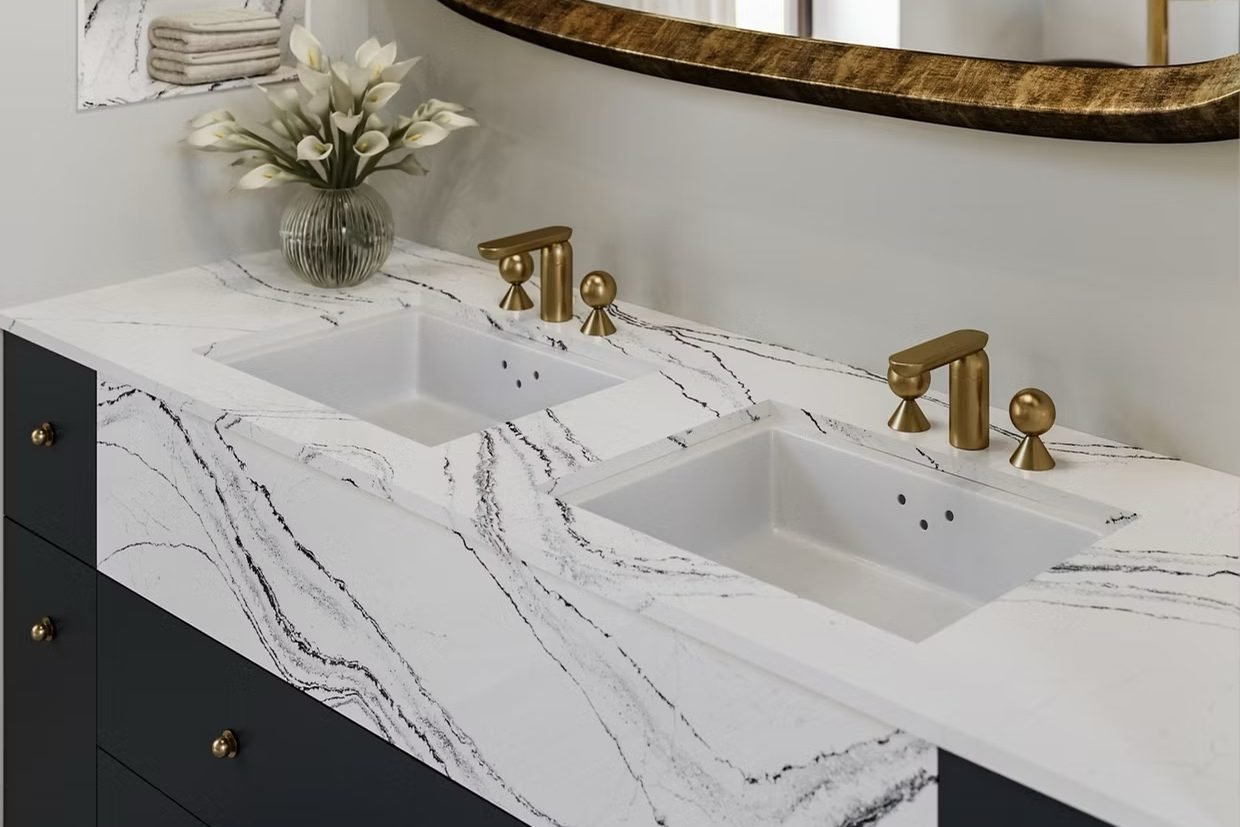 A navy double vanity topped in white quartz with bold black veining, brass faucets, and a gold framed mirror above