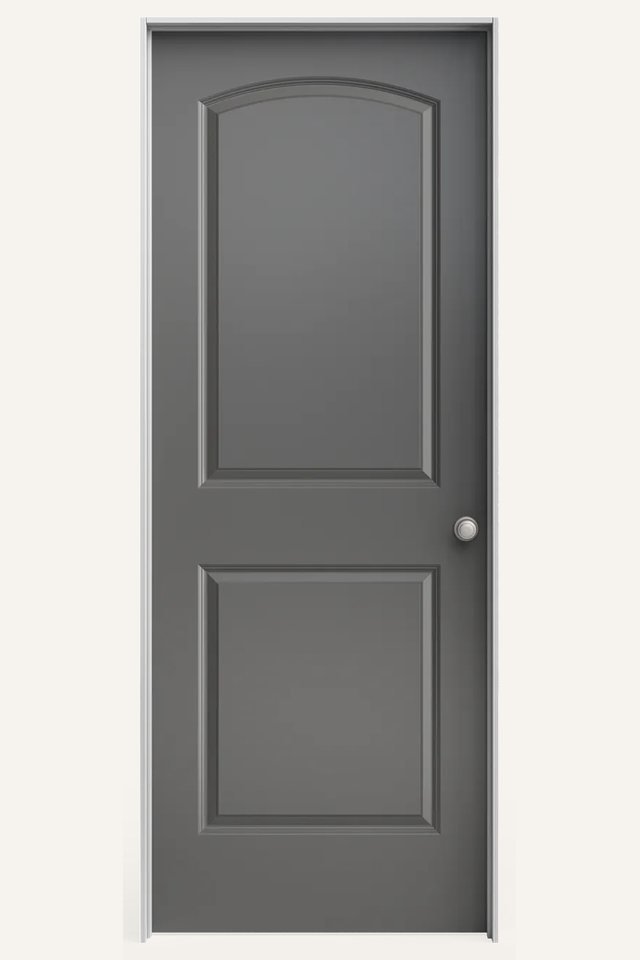 Frontal view of a closed interior 2 traditional gray panel door, the top panel arched with a silver round handle on the right side.