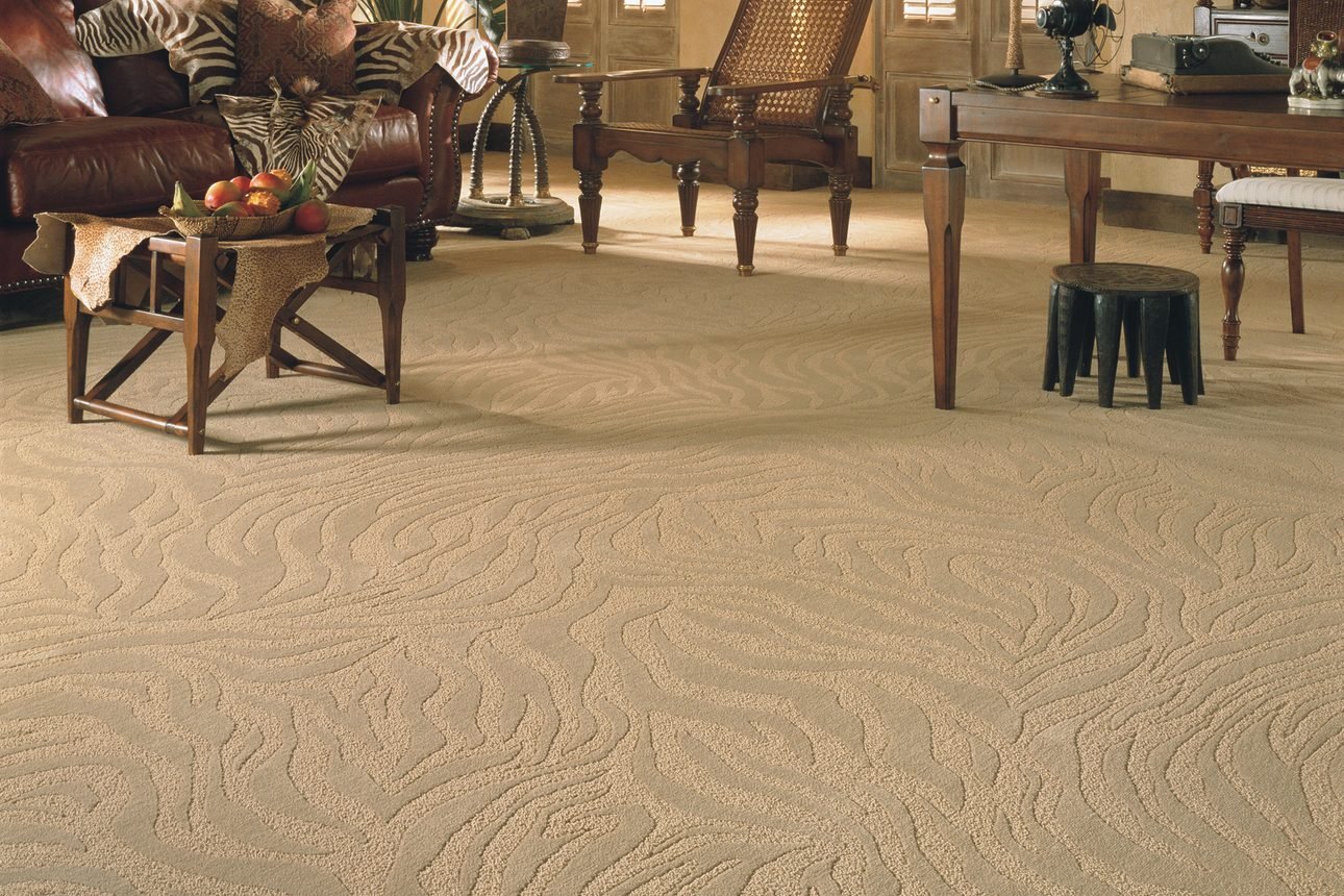 A cream cut-pile carpet with a raised swirling pattern, running wall to wall through a living room furnished with dark wood pieces and brown leather seating