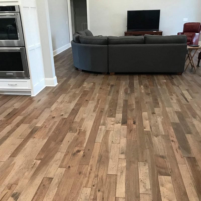 A wide plank hardwood floor in grey brown, running through an open kitchen and living room