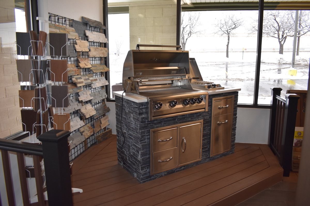 The Foothills showroom floor: an outdoor kitchen island display beside racks of stone and decking samples