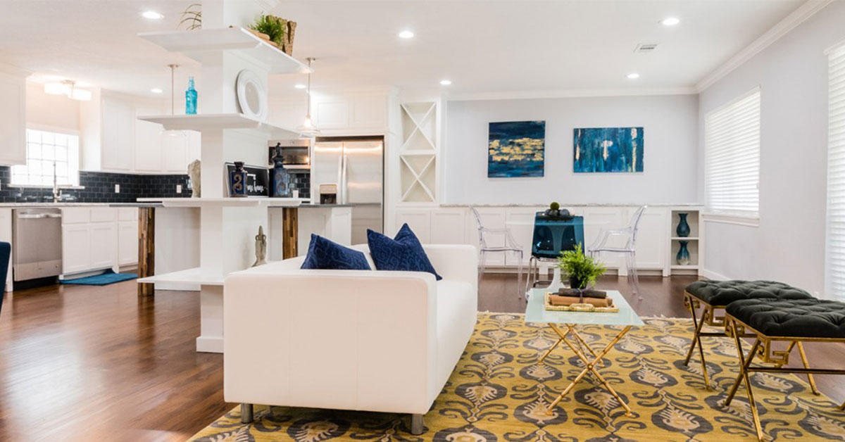A dark living room with a green marble fireplace, a framed picture above it and a round wood coffee table in front