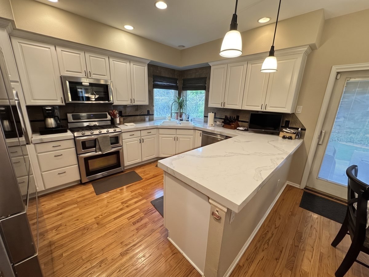 An AI preview of an oak kitchen with new white shaker cabinet doors and Calacatta Nuvo quartz counters