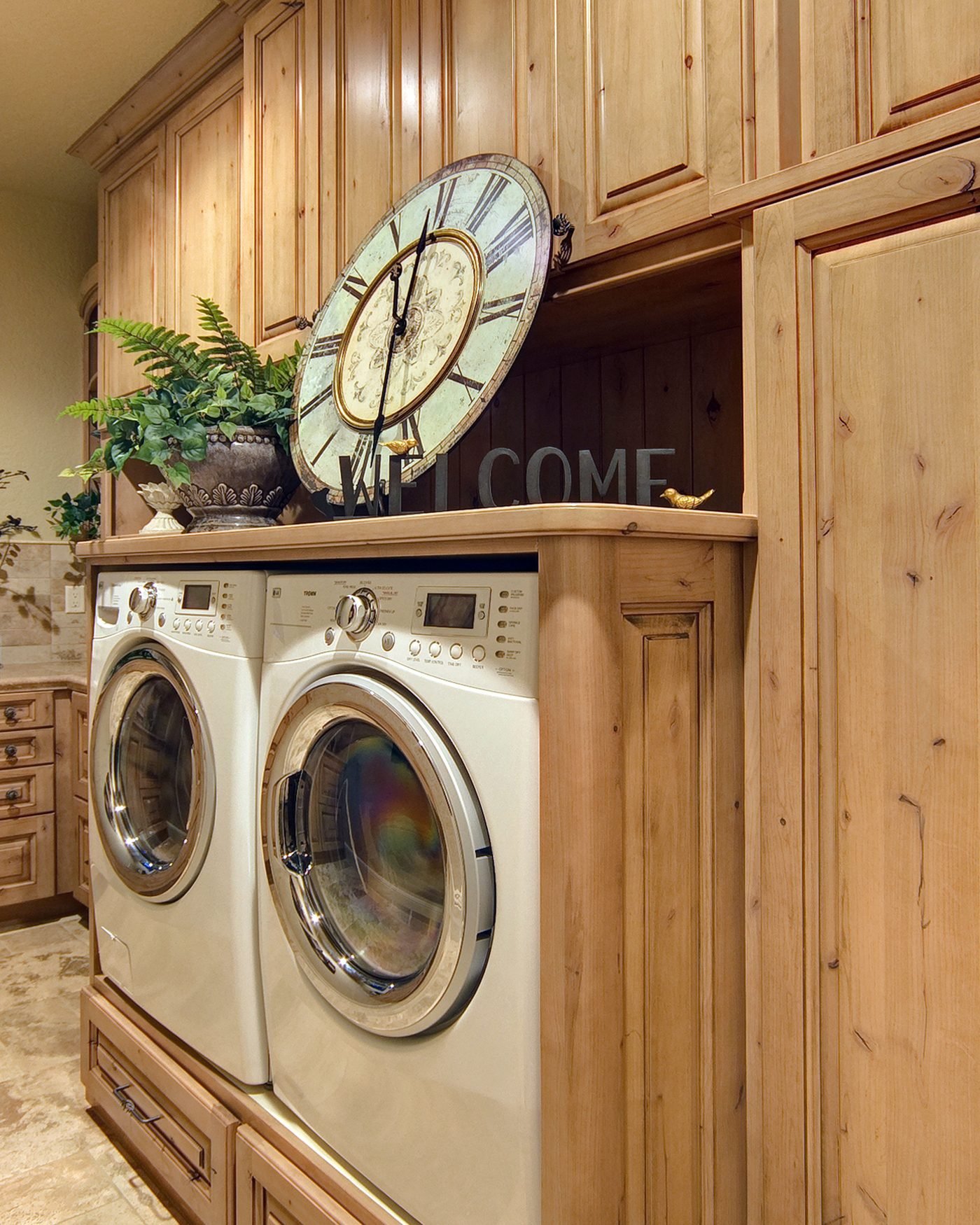 A laundry room in knotty pine cabinetry, with a front loading washer and dryer set into a run of cabinets