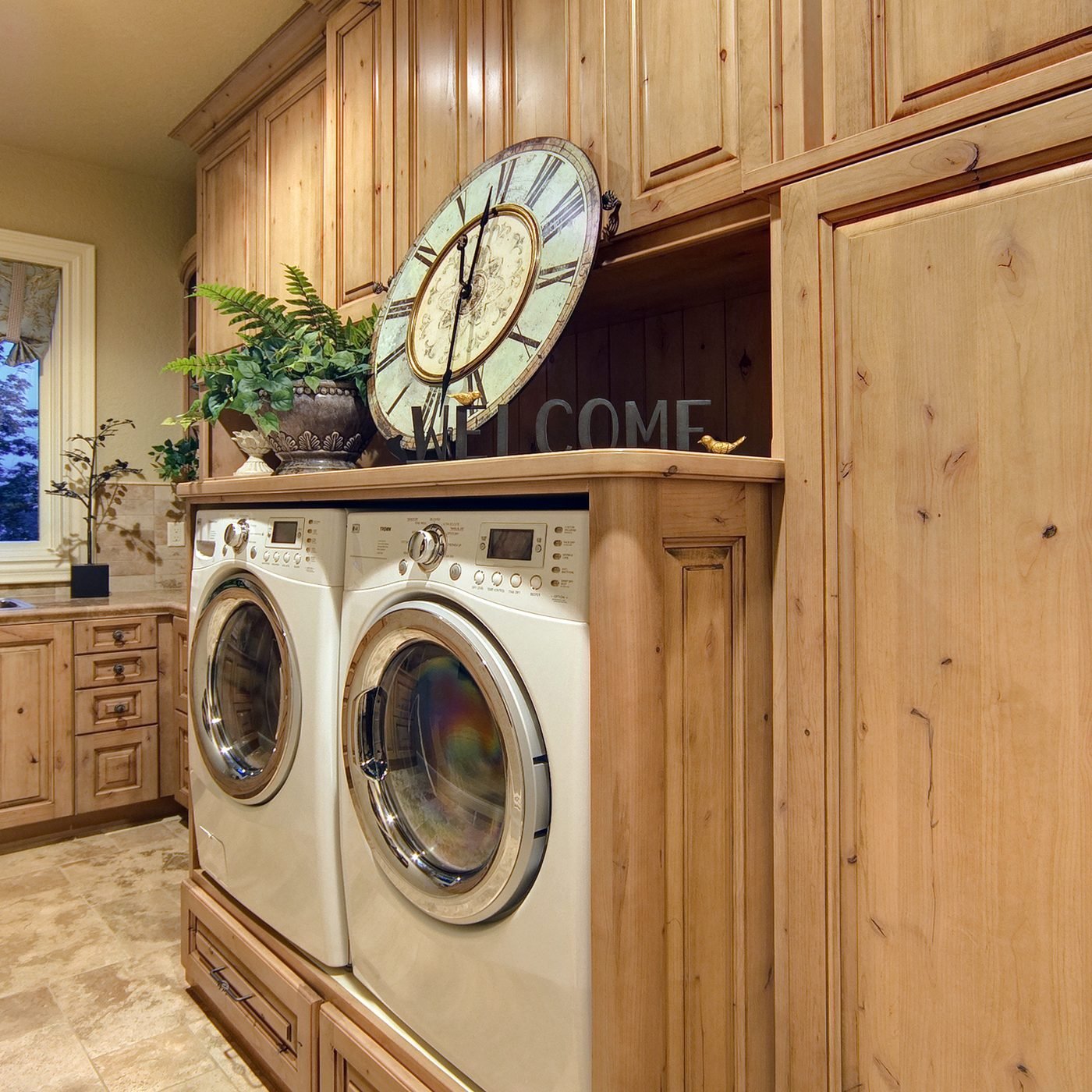 A laundry room in knotty pine cabinetry, with a front loading washer and dryer set into a run of cabinets