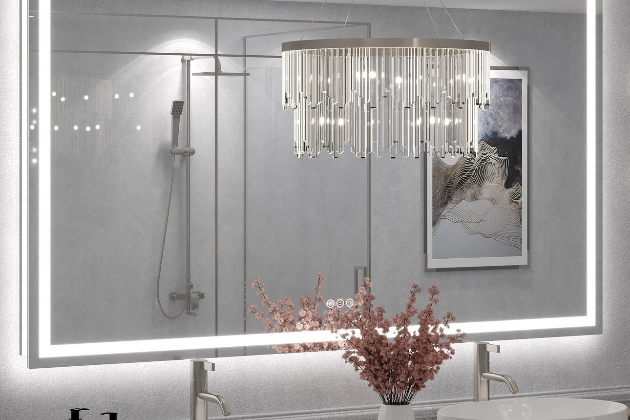 A wide backlit LED bathroom mirror over twin vessel sinks, its glowing edge lighting the wall, with a pendant reflected in the glass