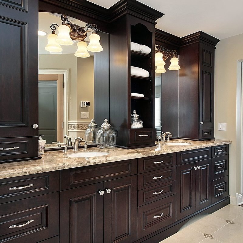 A dark espresso double vanity with a granite top, a tall storage tower between the sinks and framed mirrors