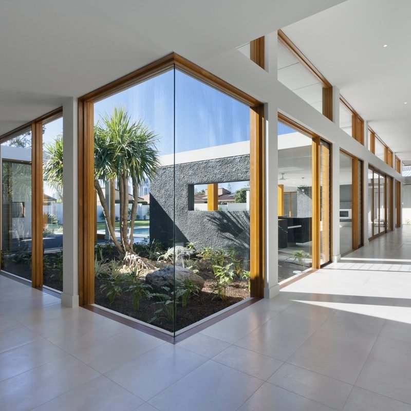 Floor to ceiling windows running down a hallway and around a planted courtyard